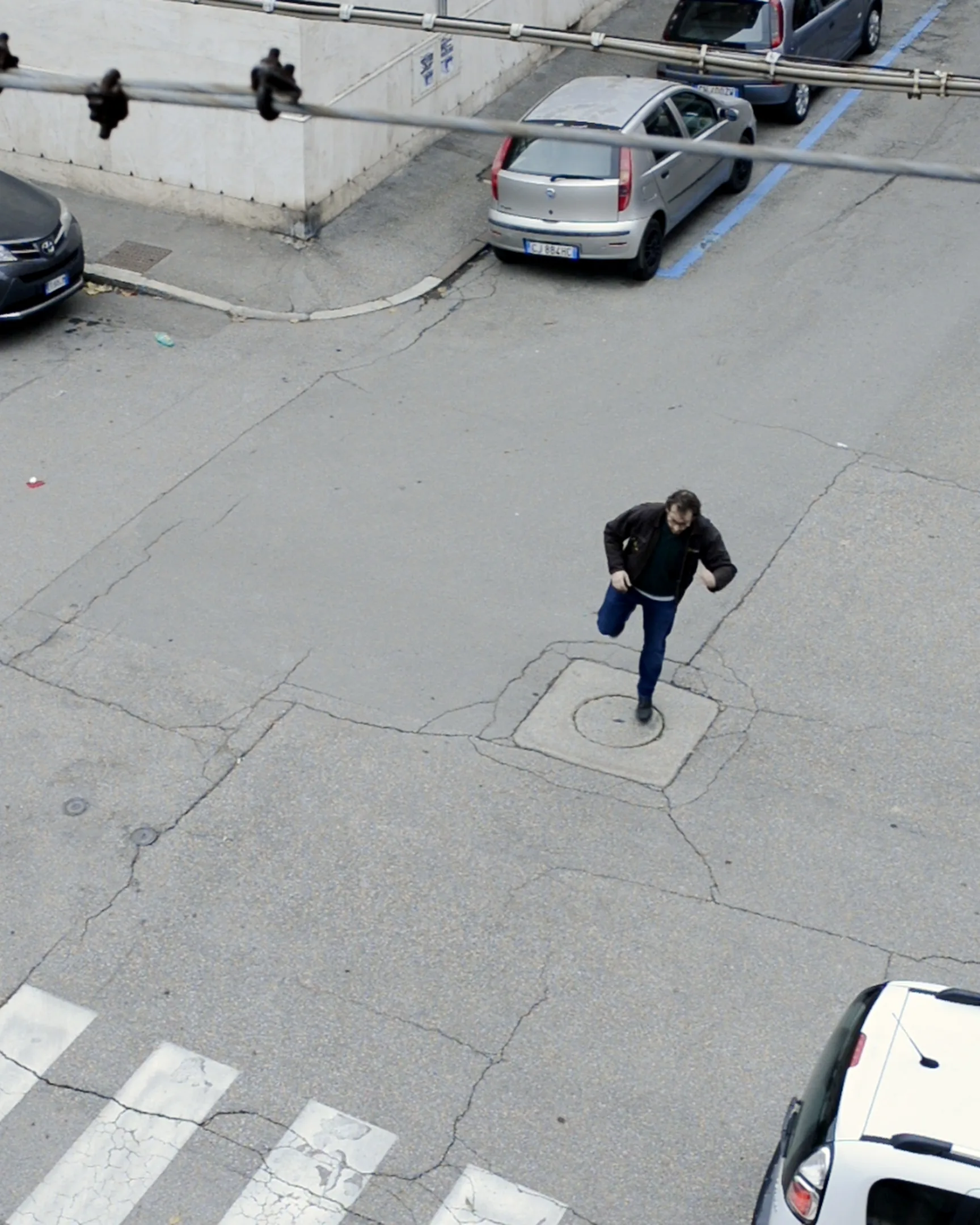 Vista dall'alto: un uomo corre sull'asfalto fra le auto